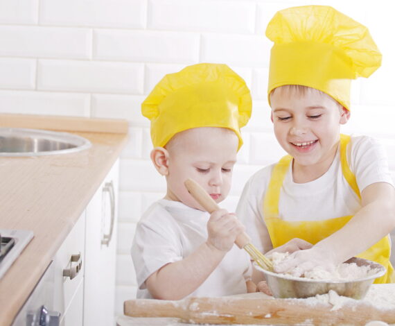 Children in cook caps prepare in kitchen